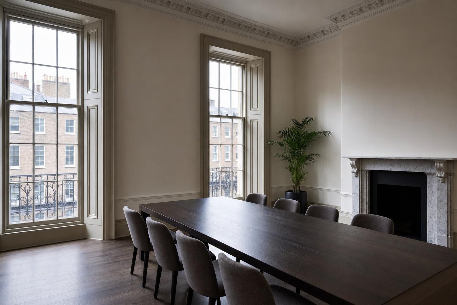 An empty meeting room on the upper floor of a Georgian townhouse, with tall sash windows and a long timber table
